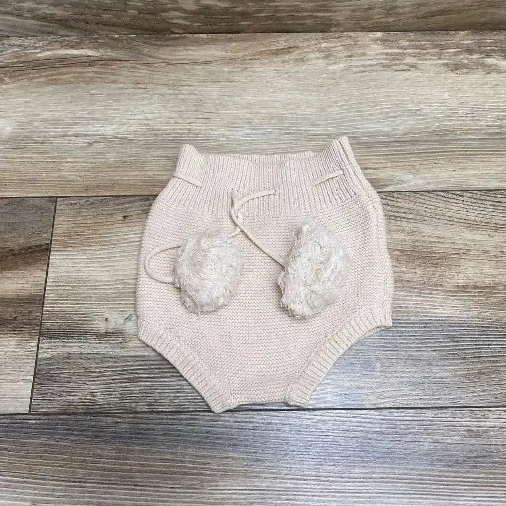 Front view of light pink Karibou Gracie Knit Bloomers sz 2T with high waist, adjustable drawstring, and pom poms on wood