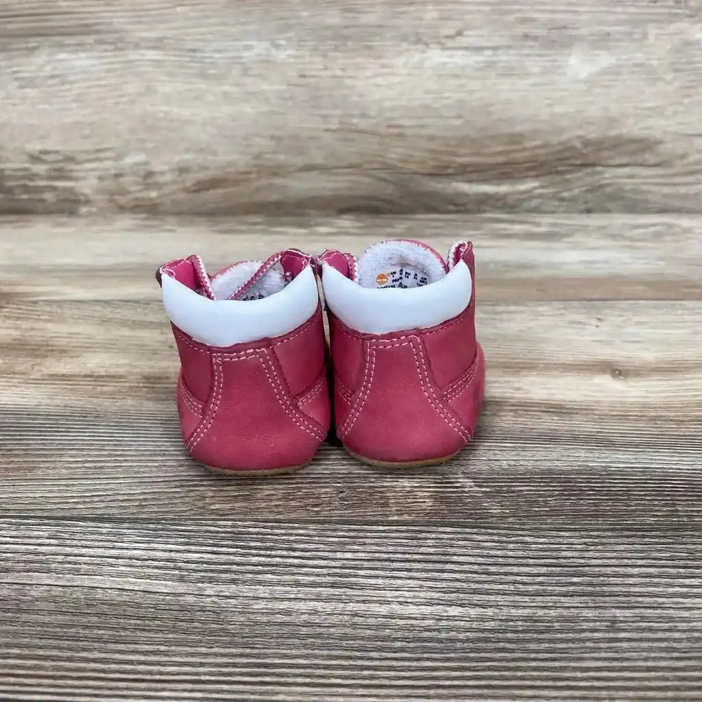 Rear view of pink Timberland infant crib booties, size 1C, showing white padded collars and stitched seams on wood background