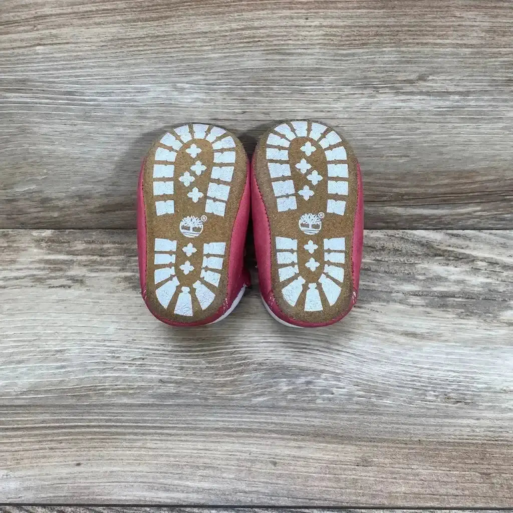 Front view of pink Timberland infant crib booties size 1C showing soft sole and ankle cuff on white background