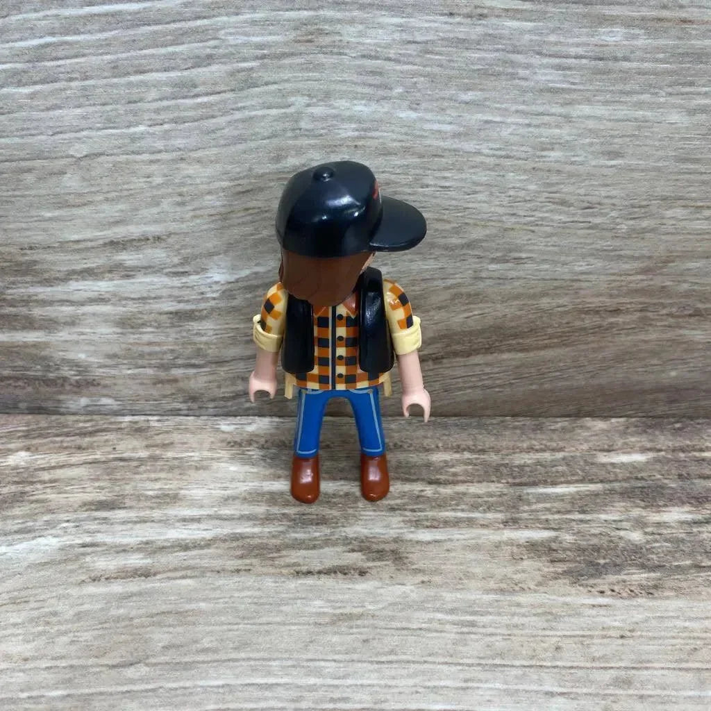 Front view of Playmobil 5665 dump truck driver figure wearing black cap and checkered shirt on woodgrain background