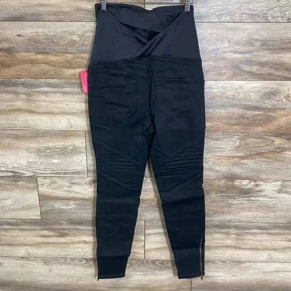 Back view of black Isabel maternity utility jeggings size 0 showing crossover belly panel, rear pockets, and ankle zippers on wood floor