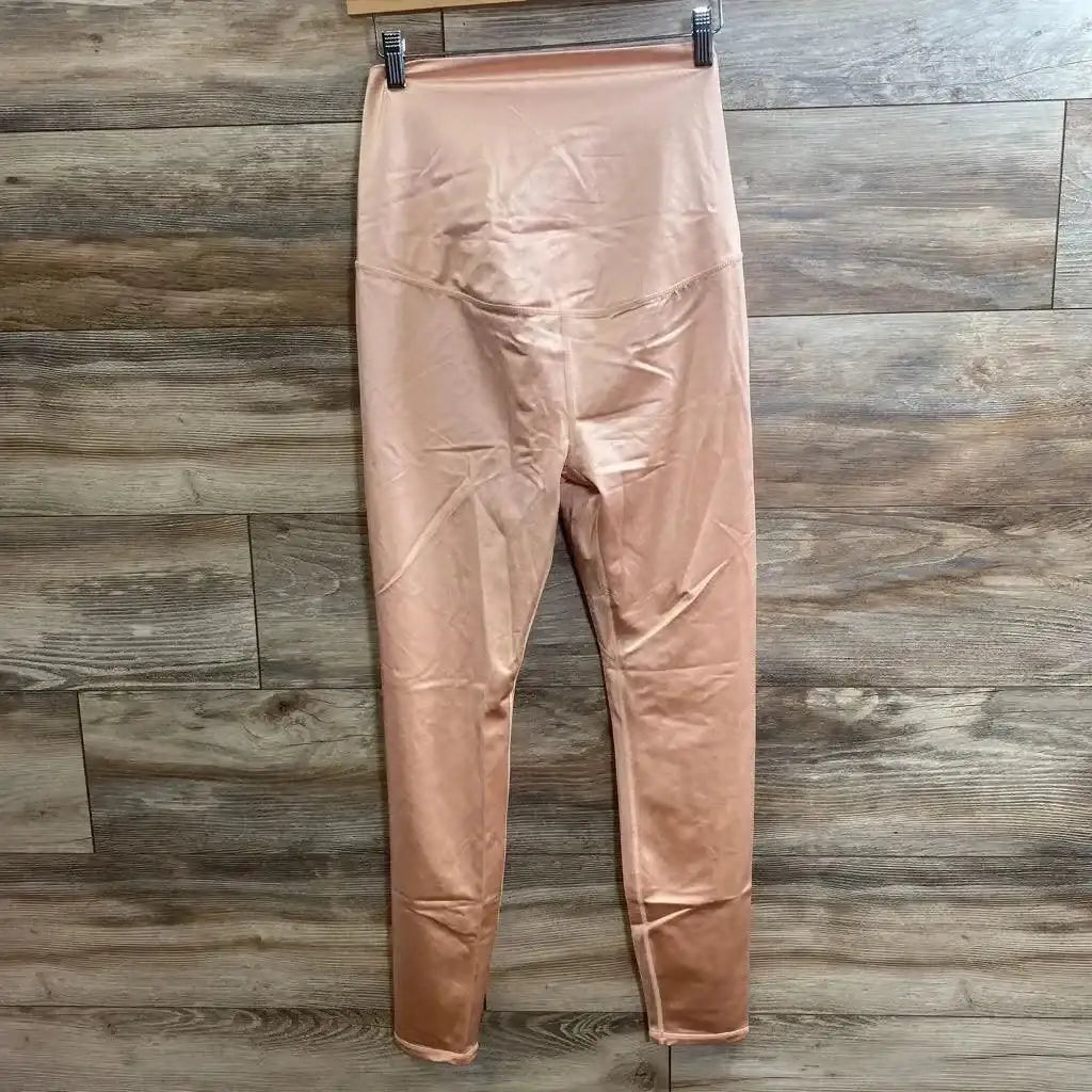Front view of pink high-waisted leggings showcasing wide waistband and full-length legs hanging on wood plank background