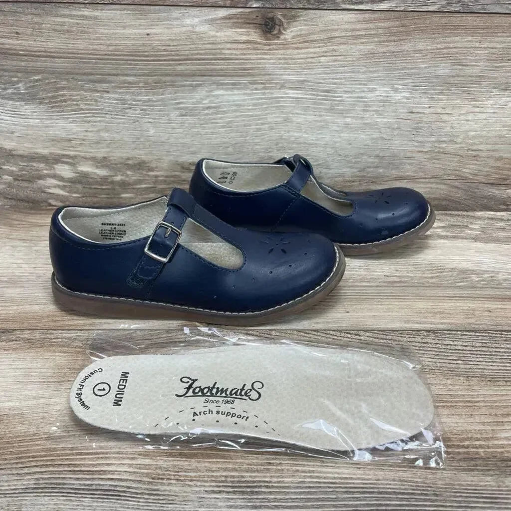 Side view of navy Footmates Sherry Mary Jane shoes showing T-strap buckle, perforated toe, with insole on wood background