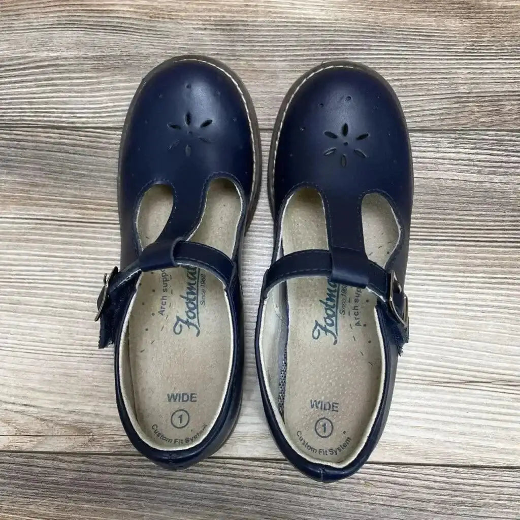 Top view of navy Footmates Sherry Mary Jane toddler shoes showing T-strap buckle, flower-toe perforation and WIDE 1 insoles on wood floor