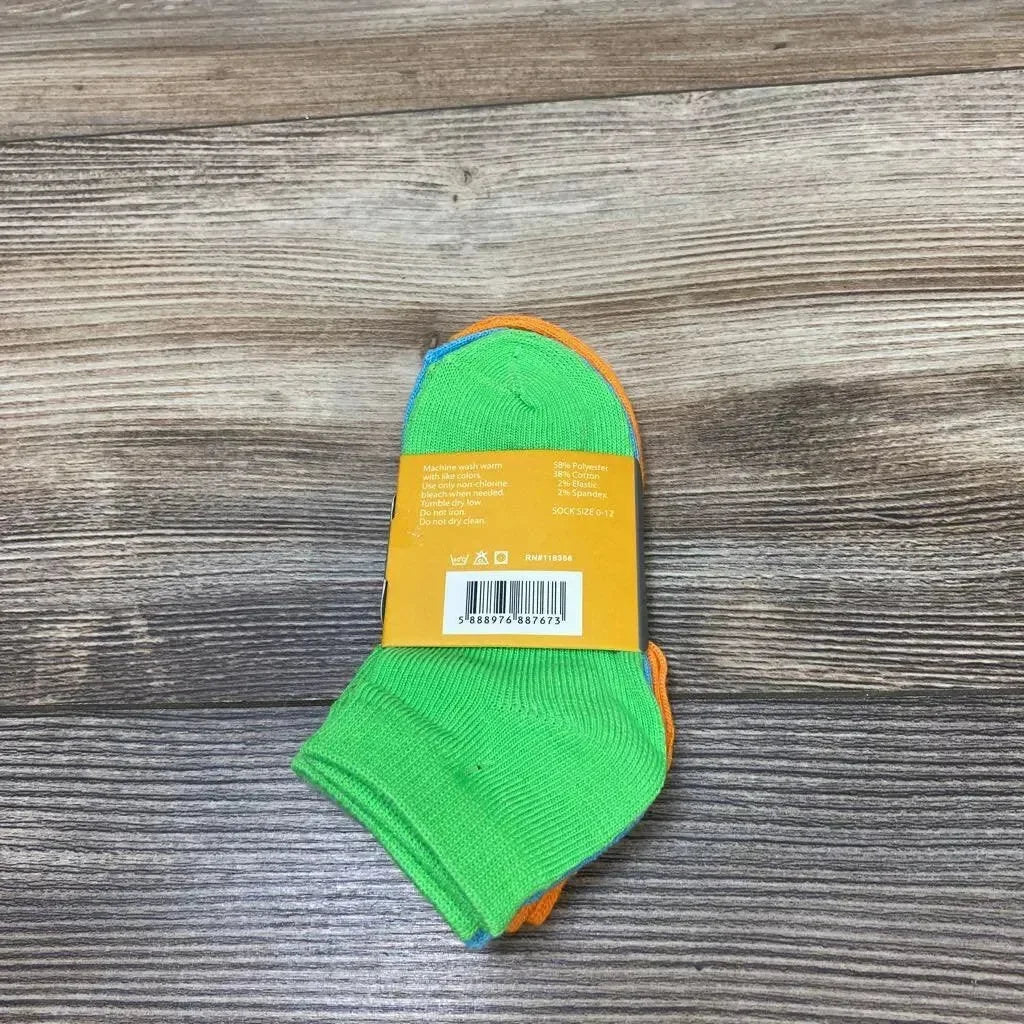 Top view of three-pack baby ankle socks showcasing solid bright green and orange colors and low-cut ankle style on wood background