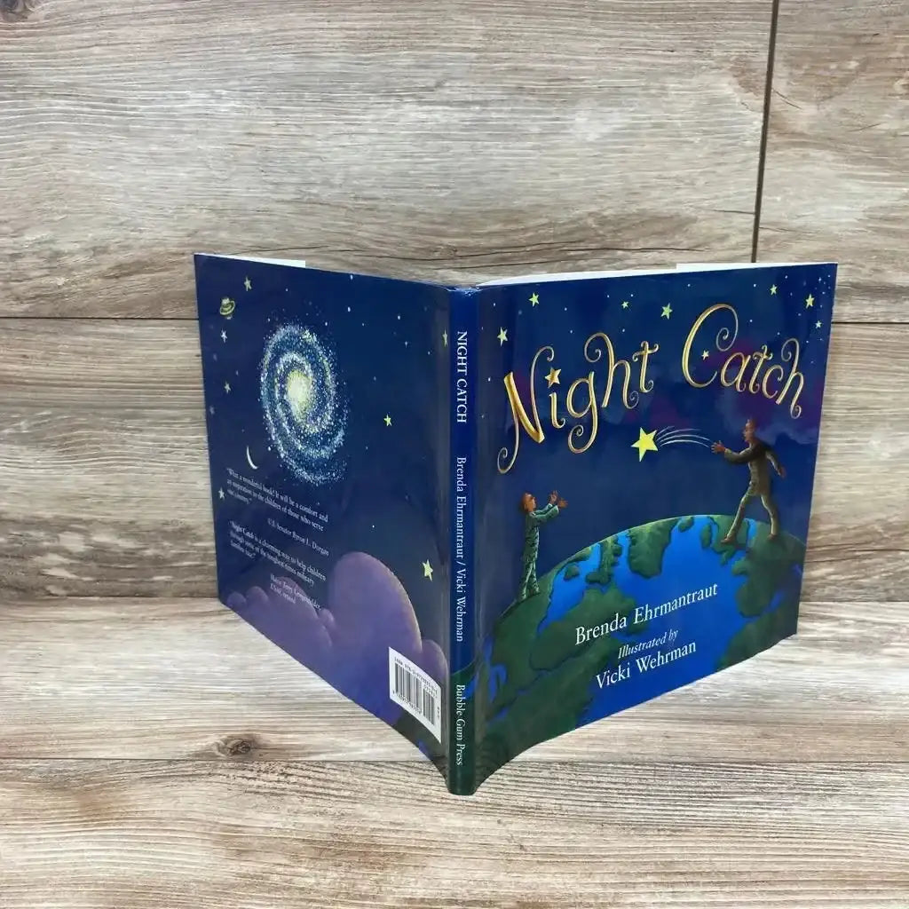 Three-quarter view of Night Catch hardcover children's book showing front cover, spine, and back with starry illustrated cover on light wood background