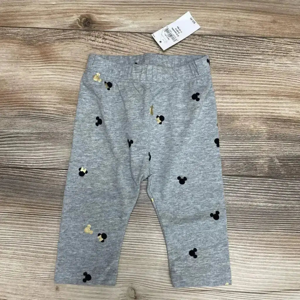 Front view of grey BabyGap leggings 0-3m showcasing black and gold Mickey and Minnie head prints on wooden floor