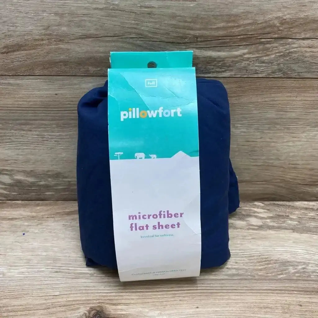 Front view of packaged navy Pillowfort microfiber flat sheet showing label reading pillowfort and microfiber flat sheet on wood surface