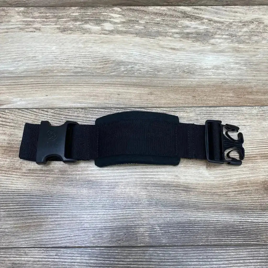 Top-down view of black LILLEbaby waistbelt extension showing padded center panel and plastic quick release buckle on wood background