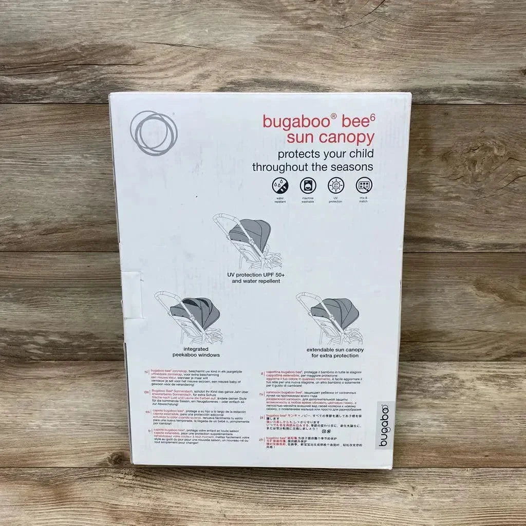 Front of Bugaboo Bee6 sun canopy box showing UPF 50 protection, water repellent, peekaboo window and extendable canopy on wood