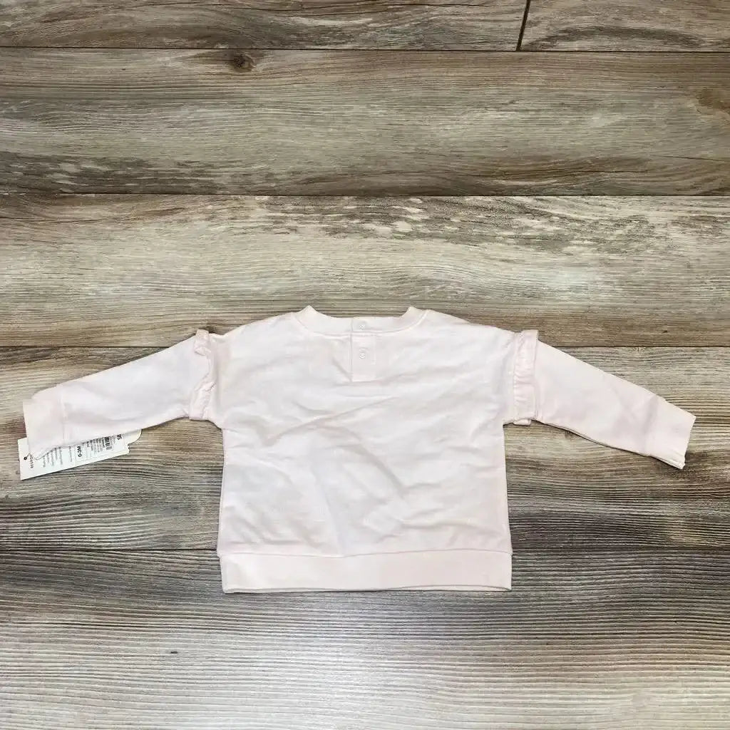 Back view of pink Cat and Jack baby sweatshirt in size 0 to 3 months showcasing long sleeves and buttoned back placket on wood grain