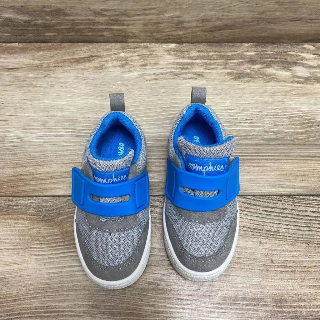 Top-down view of Oomphies Devon toddler sneakers showcasing bright blue Velcro strap and grey mesh upper on wood floor, size 7C