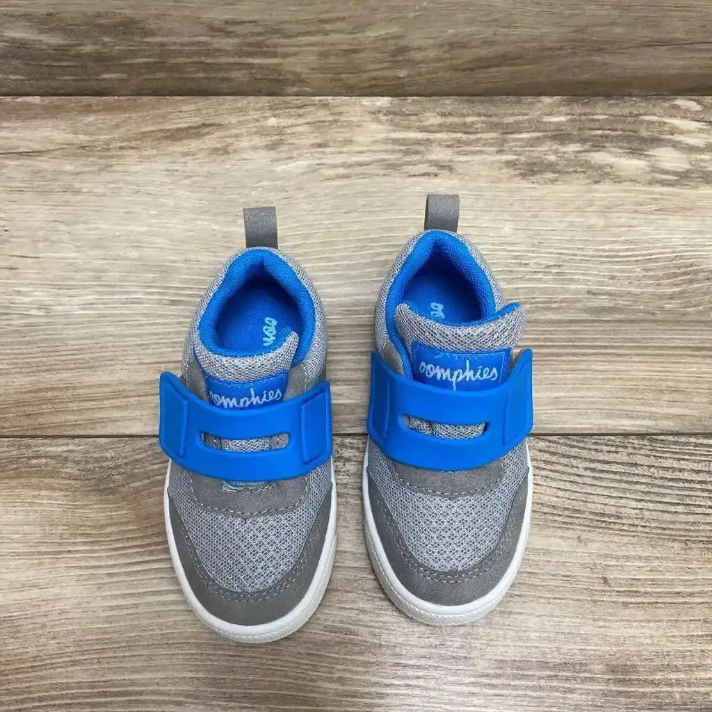Top-down view of Oomphies Devon toddler sneakers showcasing bright blue Velcro strap and grey mesh upper on wood floor, size 7C