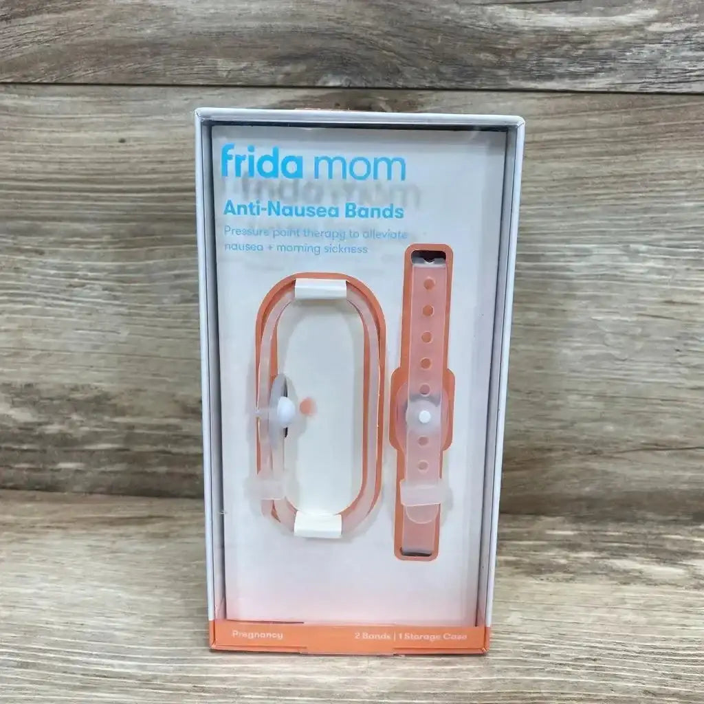 Front view of Frida Mom Anti-Nausea Bands showing two orange bands with white pressure studs and case on wood background