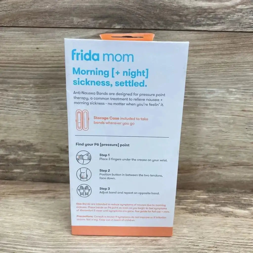 Back of Frida Mom Anti-Nausea Bands box showing pressure-point instructions and included storage case on wood background