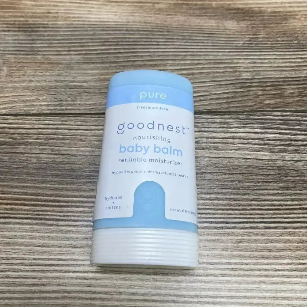 Front view of Goodnest nourishing baby balm stick showing refillable fragrance free label and 0.6 oz size on light wood background