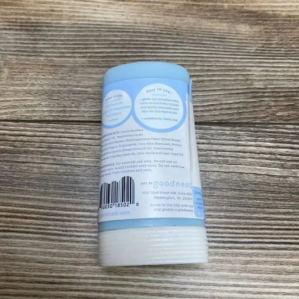 Rear view of Goodnest Moisturizing Baby Balm stick showing ingredient list, usage instructions, and barcode on a wood surface