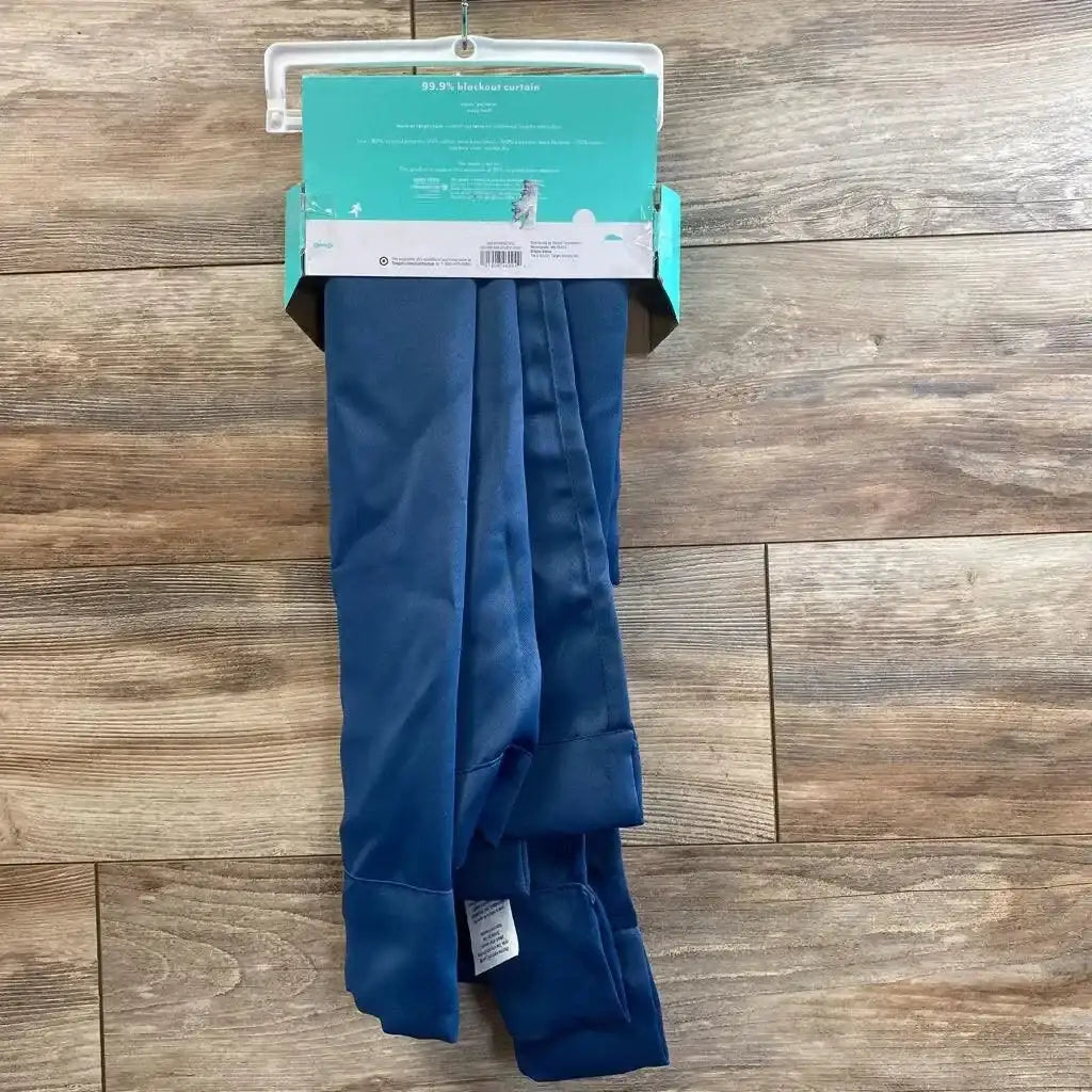 Front view of folded navy 42x84 Pillowfort blackout curtain on hanger with packaging label and blackout lining on wood floor