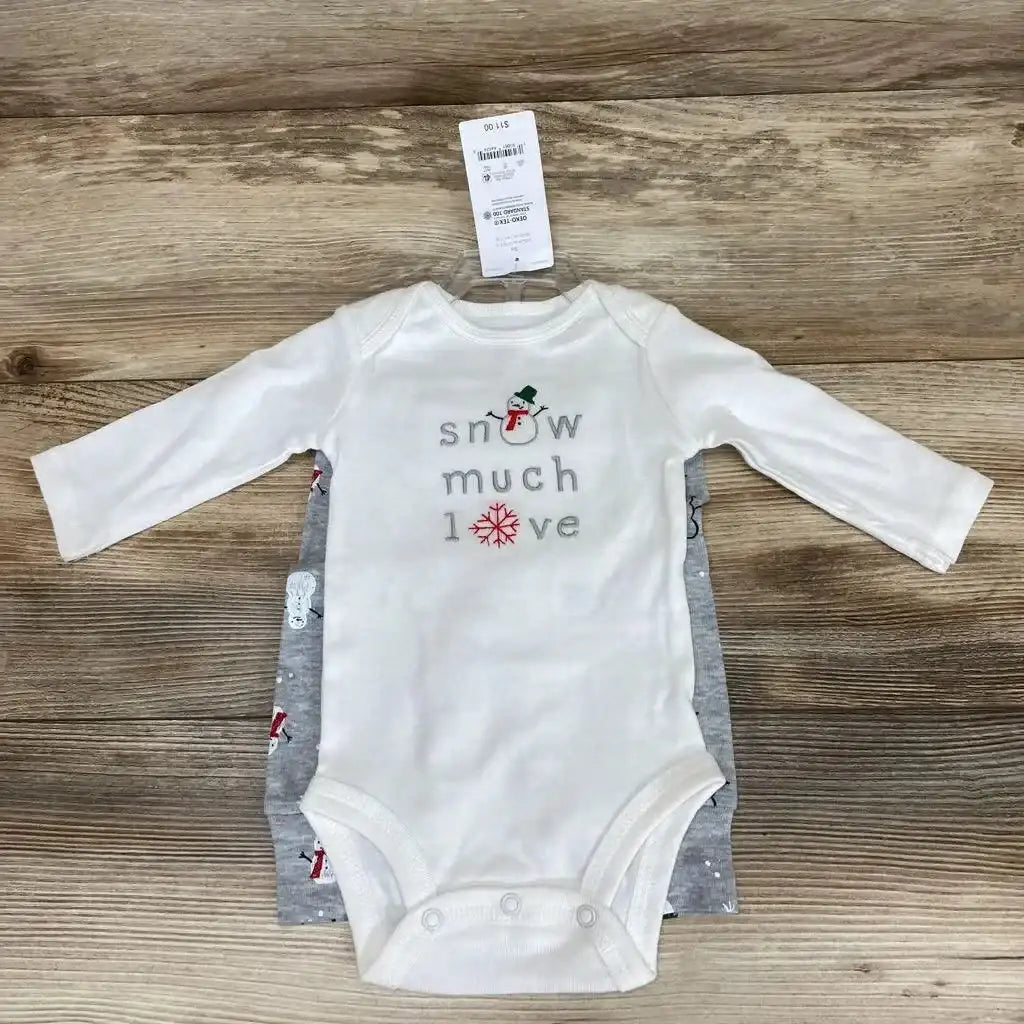 Top-down of white long-sleeve bodysuit reading snow much love with snowman and snowflake, over grey printed bodysuit on wood