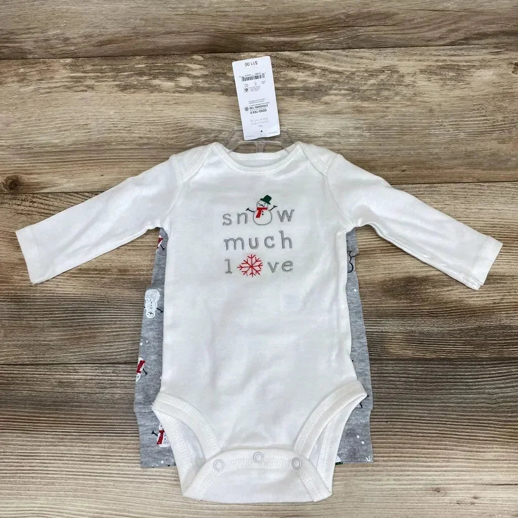 Top-down of white long-sleeve bodysuit reading snow much love with snowman and snowflake, over grey printed bodysuit on wood