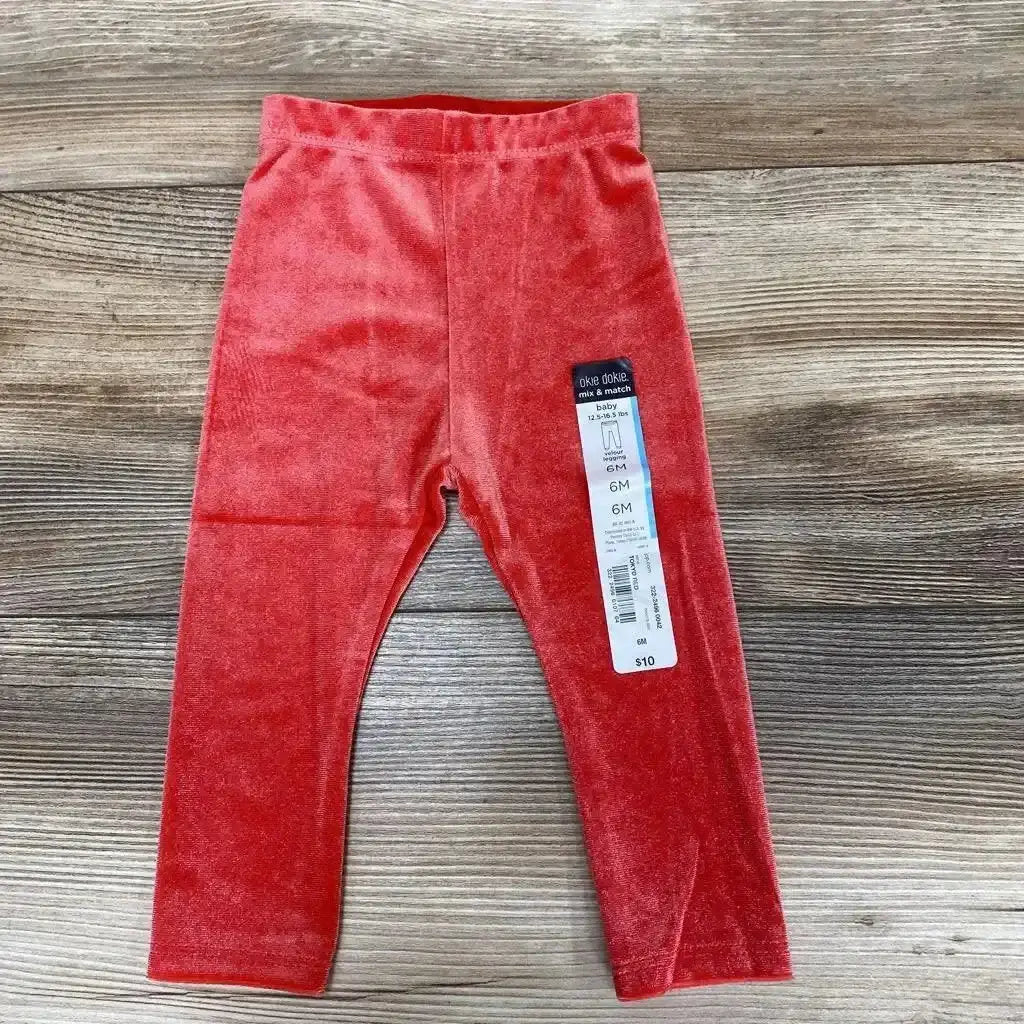 Front view of NEW Okie Dokie velour leggings showcasing red velour fabric and elastic waistband on a wood plank background