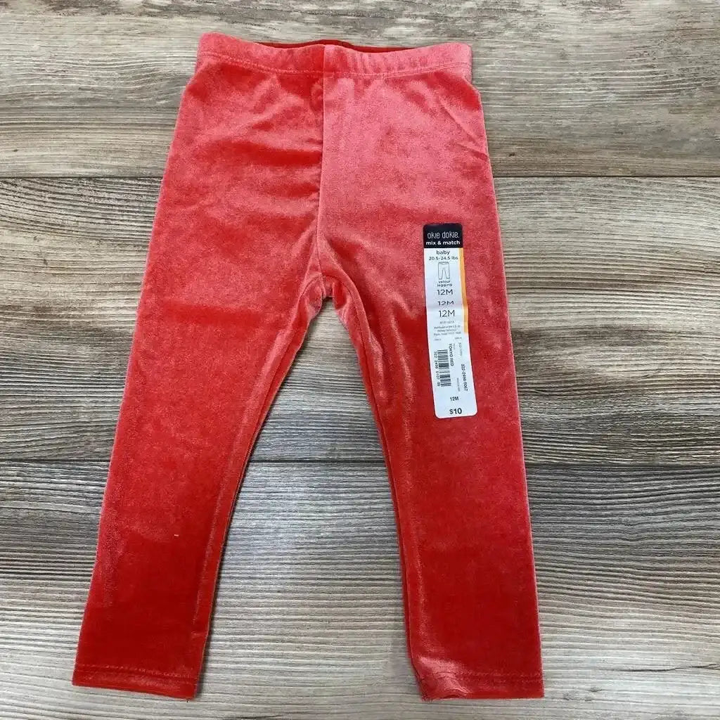 Flat lay of red Okie Dokie velour baby leggings (12M) showcasing elastic waistband and soft velour texture on wood background