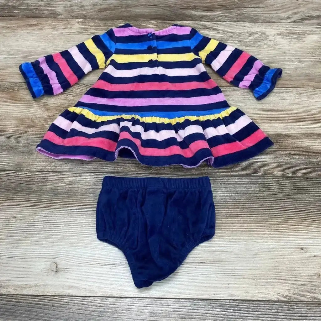 Flat lay of baby striped dress and navy bloomers showing ruffled hem, cuffed sleeves and back buttons on wood background