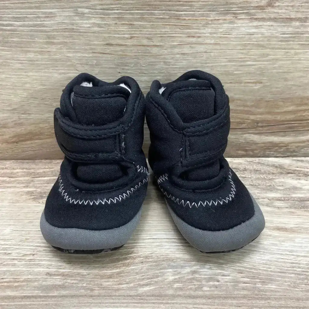Front view of Bogs Elliot II Boots size 2c showcasing black fabric uppers with hook and loop straps grey rubber soles and white zigzag stitching on wood plank floor