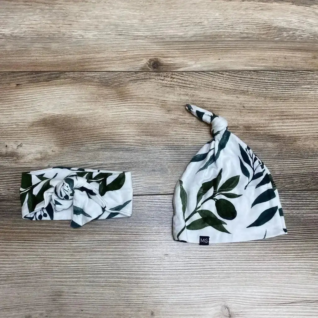 Top view of Oliver headwrap and knot hat showcasing leafy print on a wood-grain background