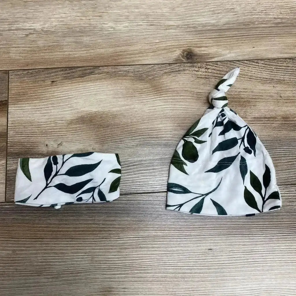 Top view of the Oliver knotted hat and adjustable headwrap set showcasing a leafy pattern on a wood background
