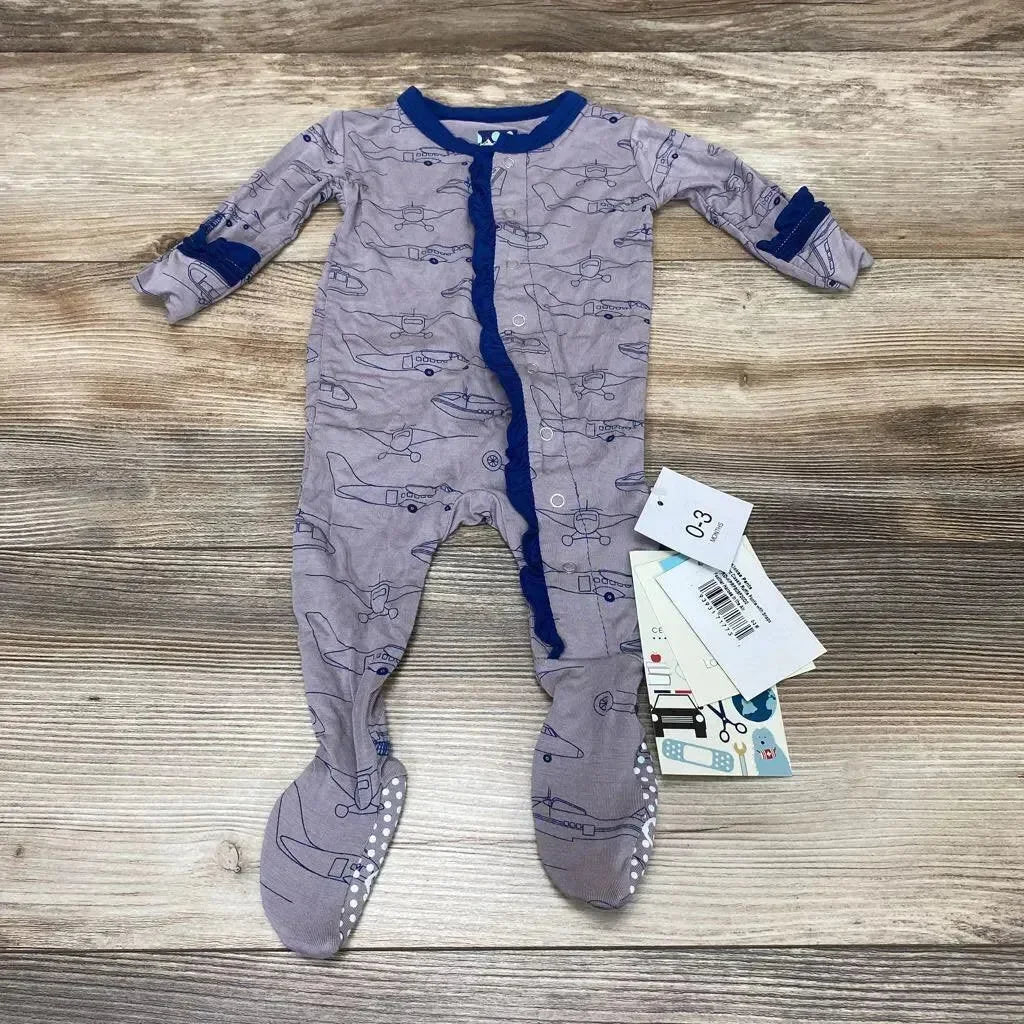 Flat lay of Kickee Pants ruffle snap footie, grey with navy trim and airplane print, gripper soles and size tag on wood