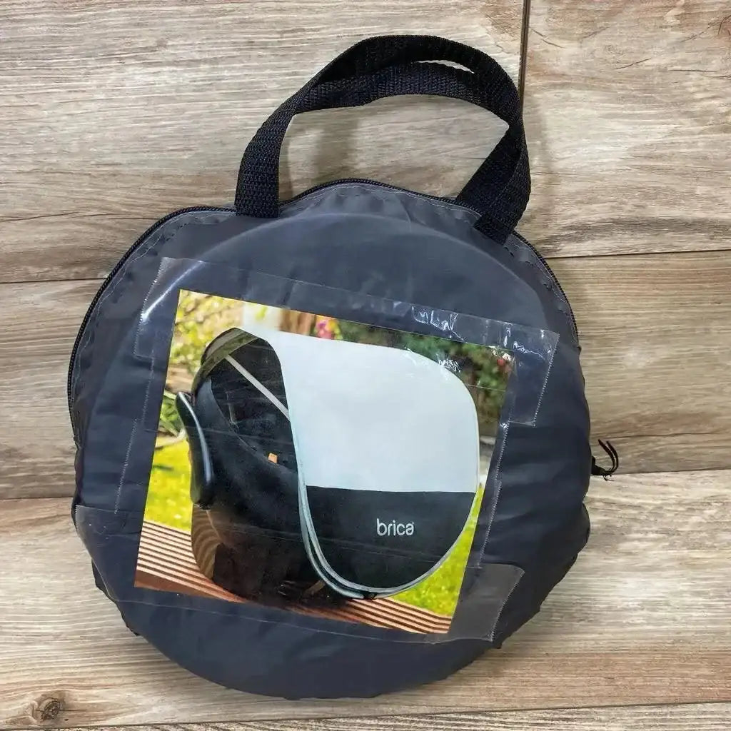 Front view of grey Brica infant car seat comfort canopy in round carry pouch showcasing photo label with wood floor background