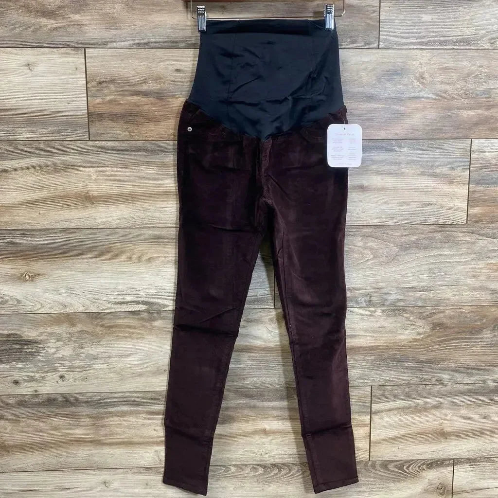 Front view of burgundy Isabel maternity skinny jeans size 00 showing crossover belly panel, hanging on wood plank background