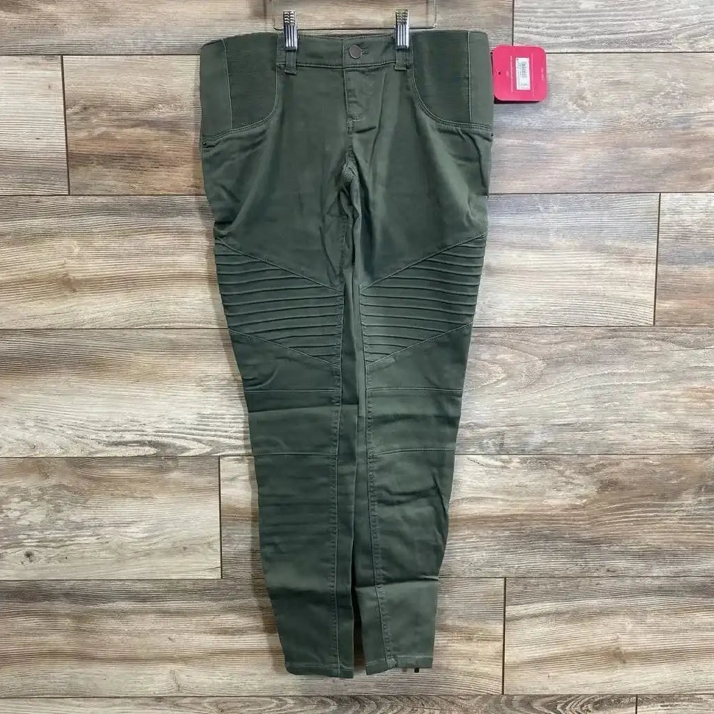 Flat lay of olive maternity utility jeggings showcasing ribbed moto knee panels, stretch side belly panels and front pockets on wood plank floor