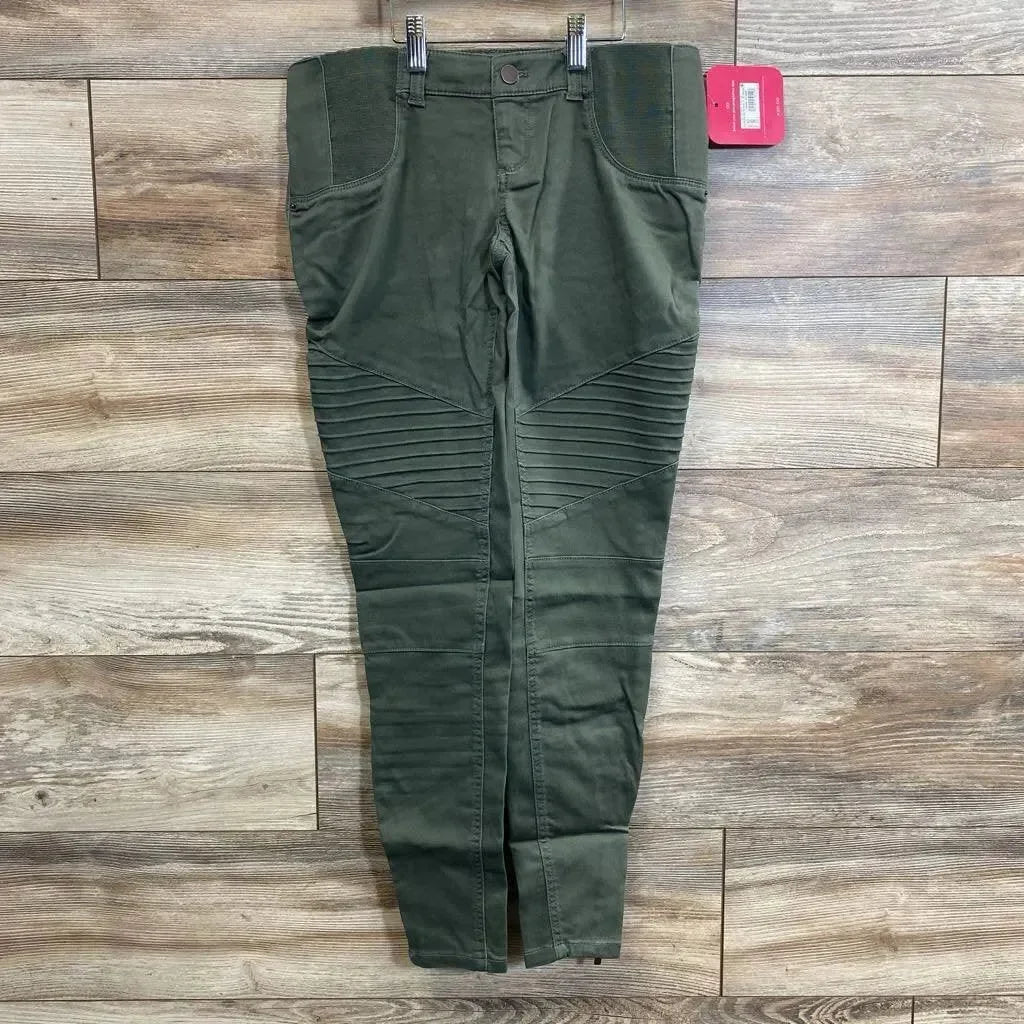 Flat lay of olive maternity utility jeggings showcasing ribbed moto knee panels, stretch side belly panels and front pockets on wood plank floor