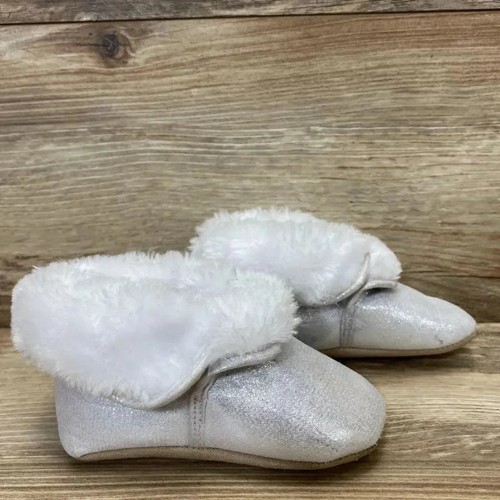 Angled view of silver baby ankle booties size 4C with glitter shimmer and white faux fur cuff on wood background