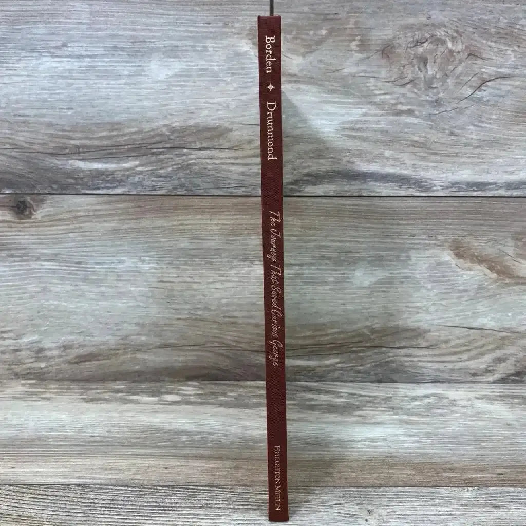Spine view of The Journey That Saved Curious George hardcover, brown cloth spine with gold title on wood background