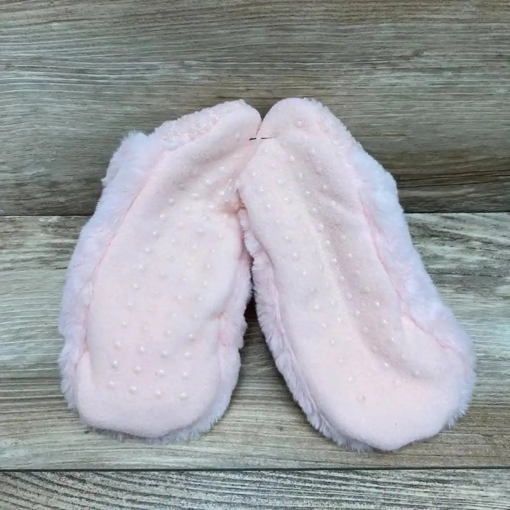 Top view of pink faux-fur baby/toddler slippers showcasing gripper-dot non-slip soles on wood-plank background