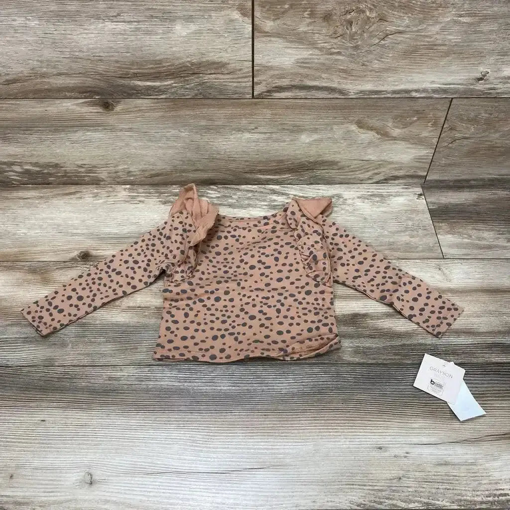 Flat lay of brown spotted Grayson mini ruffle top (18m) showing shoulder ruffles and long sleeves on wood floor