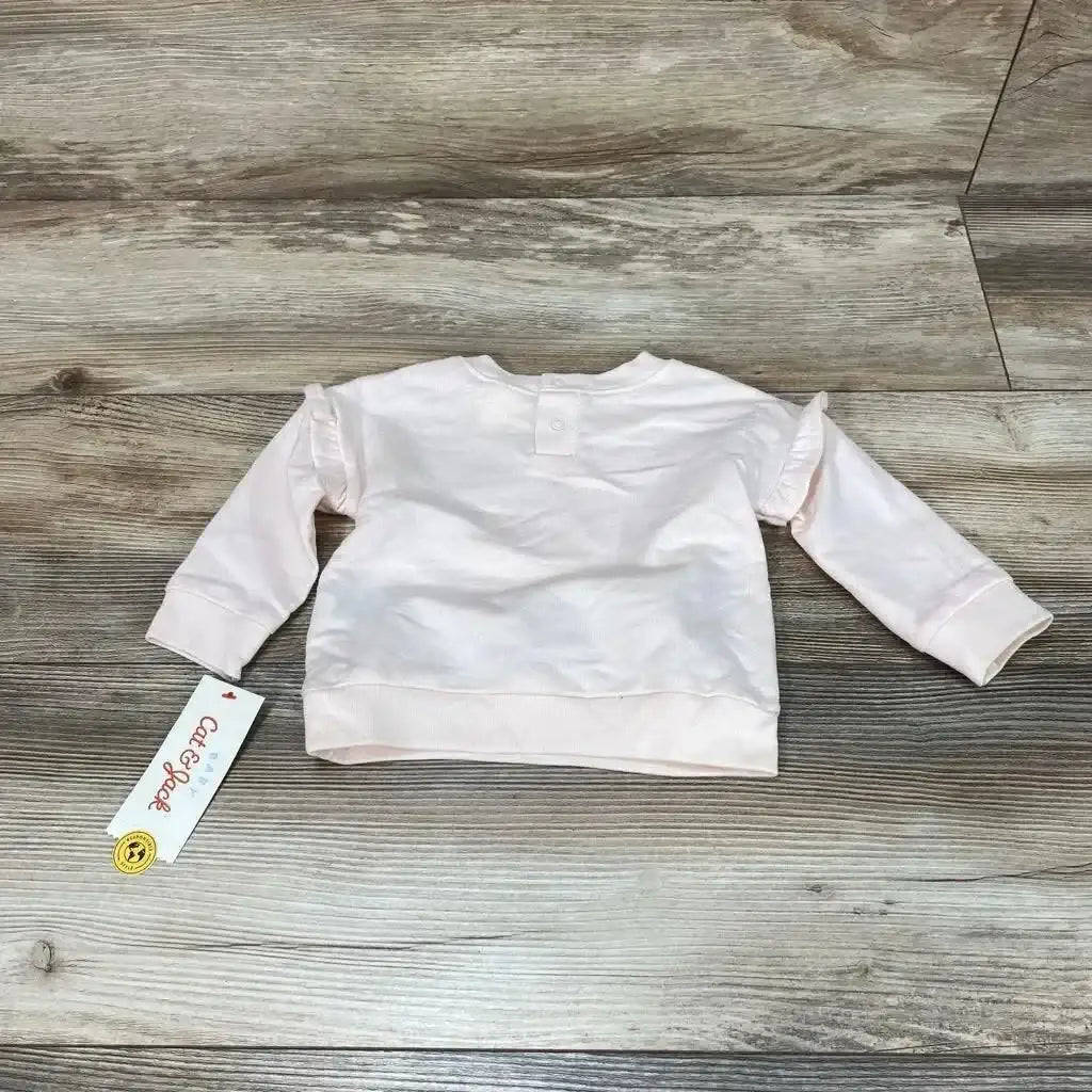 Back view of light pink Cat & Jack baby sweatshirt (3-6 months) showing ruffle-trim sleeves and tag on wood background