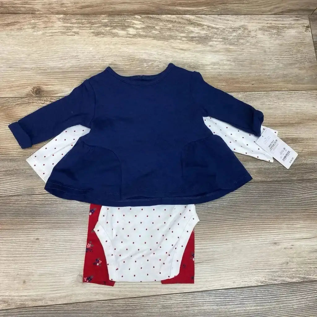 Flat lay of navy long-sleeve tunic with white polka-dot bodysuit and red floral pants, 3-piece baby set on wood background