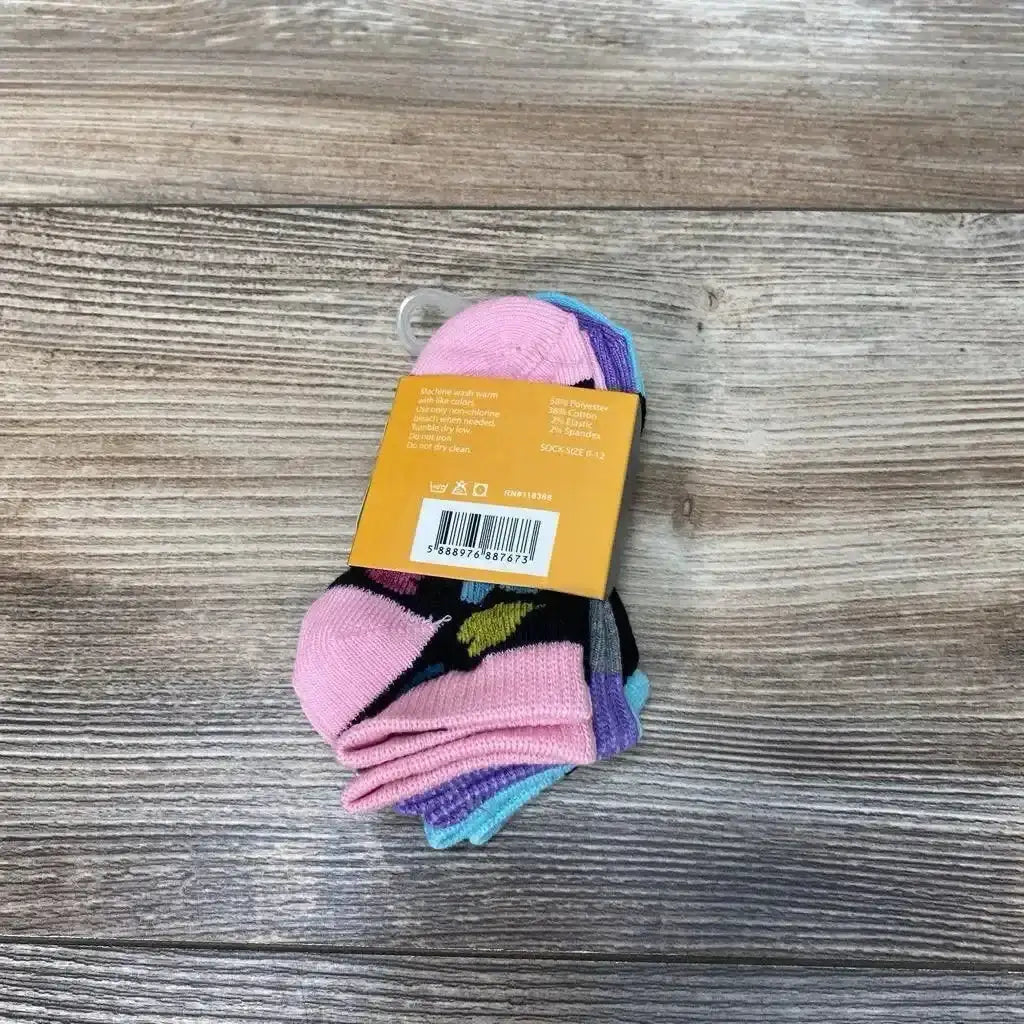 Top-down view of three folded 0-12m baby socks in pink, purple, and teal held by original cardboard band with barcode on wood background