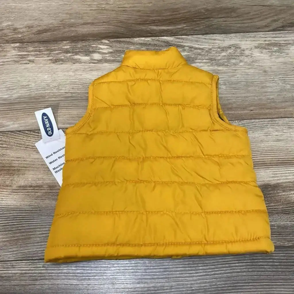 Back view of yellow Old Navy baby puffer vest 0-3 months showing quilted horizontal baffles and stand collar on wood floor