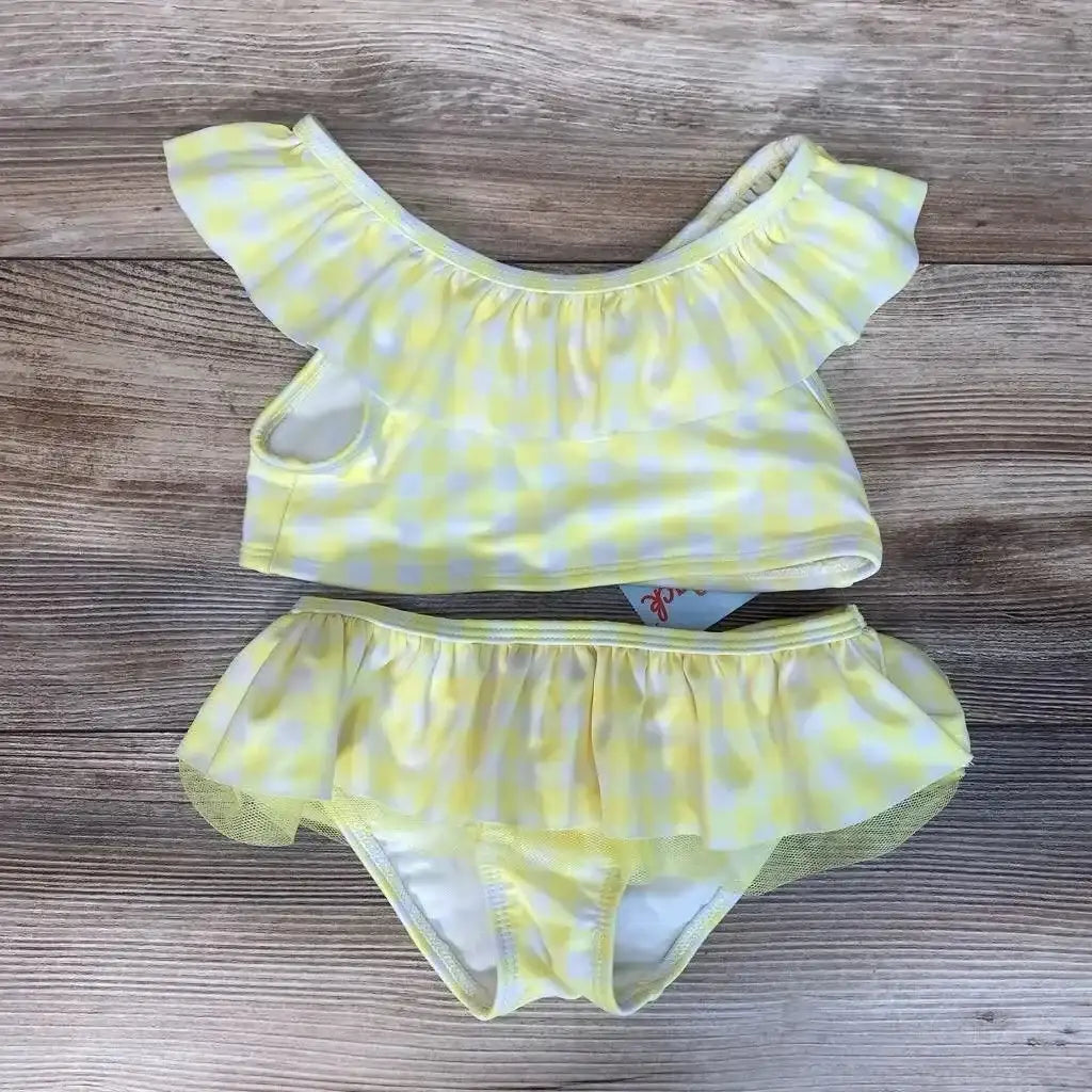Flat-lay of size 4T toddler yellow gingham 2-piece bikini with ruffle neckline and skirted bottoms on wood background