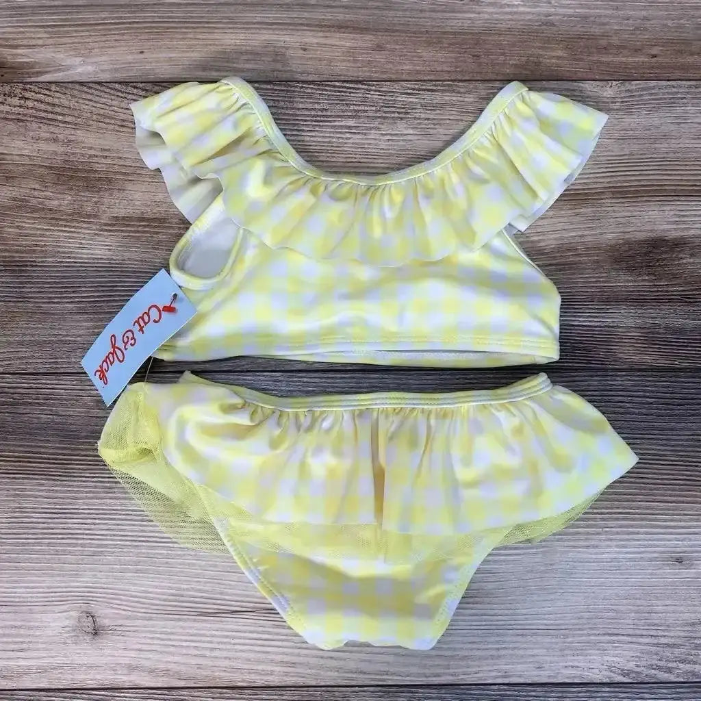 Flat lay of NEW Cat & Jack 2pc Gingham Bikini Set sz 4T showcasing yellow and white gingham ruffle top and skirted bottoms with hangtag on wood plank floor