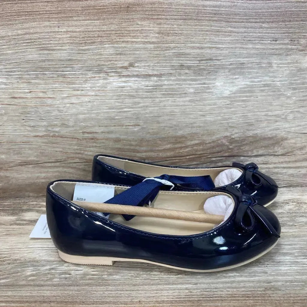 Side view of pair of navy patent bow ballet flats size 9C showing patent finish and toe bows on wood-grain surface