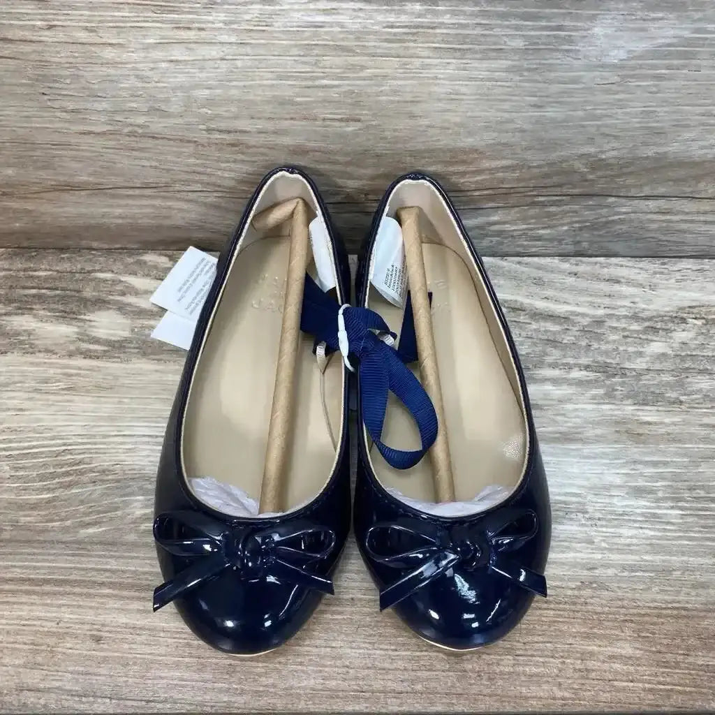 Top view of Janie and Jack patent bow ballet flats in navy with grosgrain ribbon ties and hangtags on wood plank background
