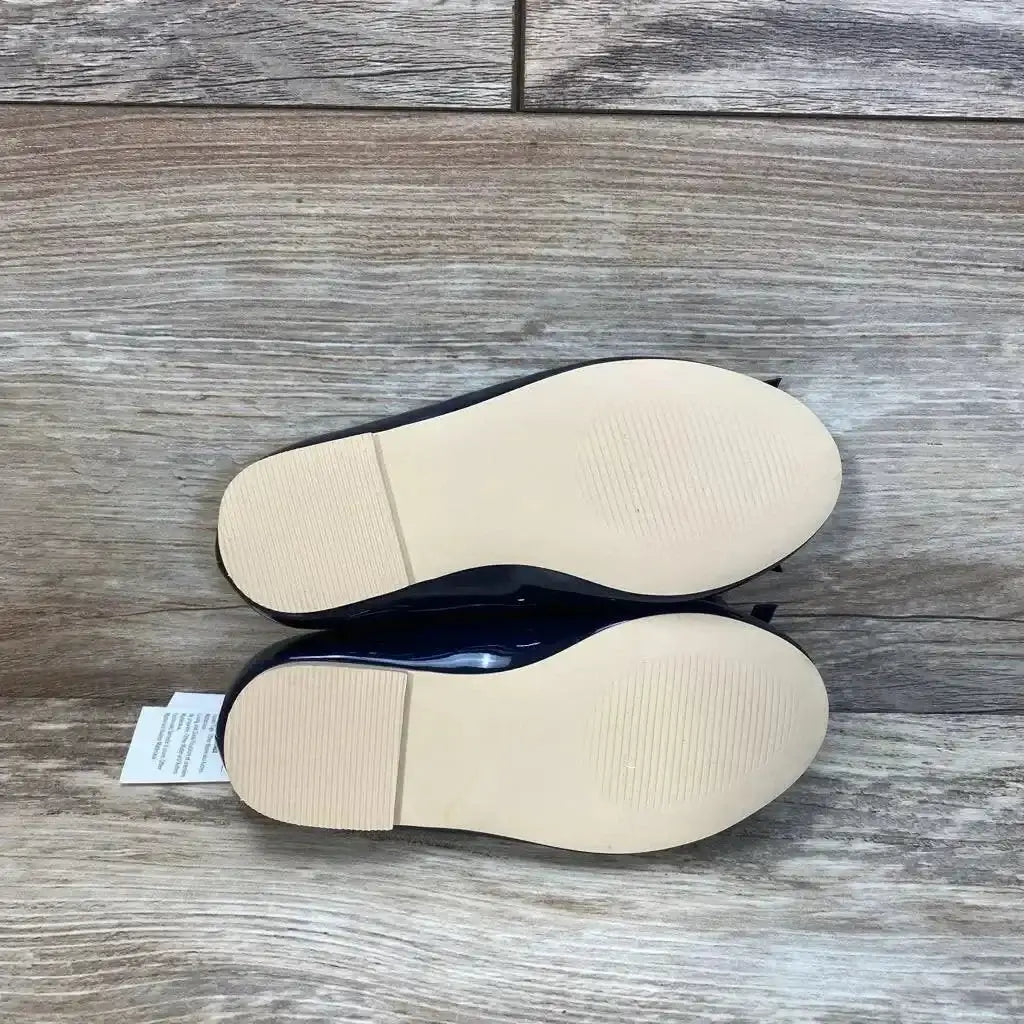 Bottom view of navy Janie and Jack patent bow ballet flats showing clean beige soles and low stacked heel on wood background