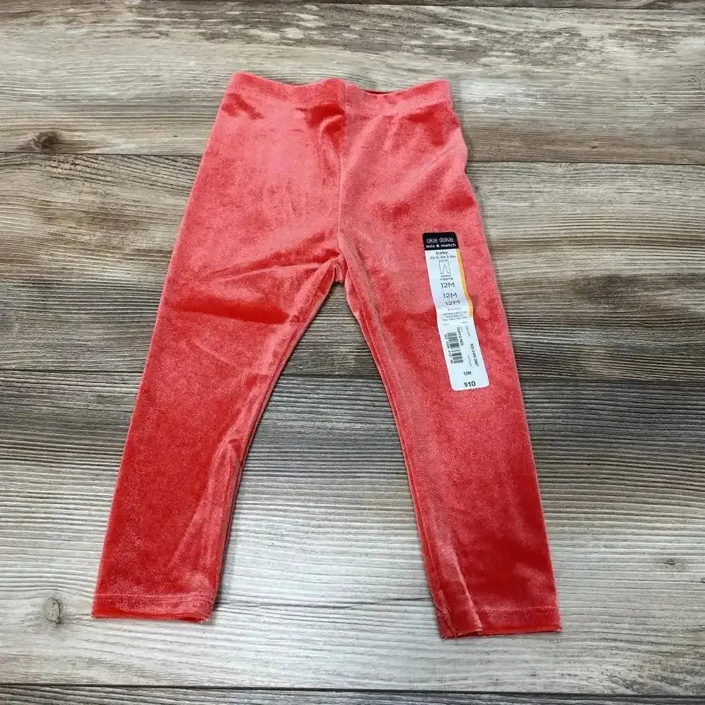 Front view of NEW Okie Dokie velour leggings, size 12M, showcasing the red velour fabric on a wood-grain background