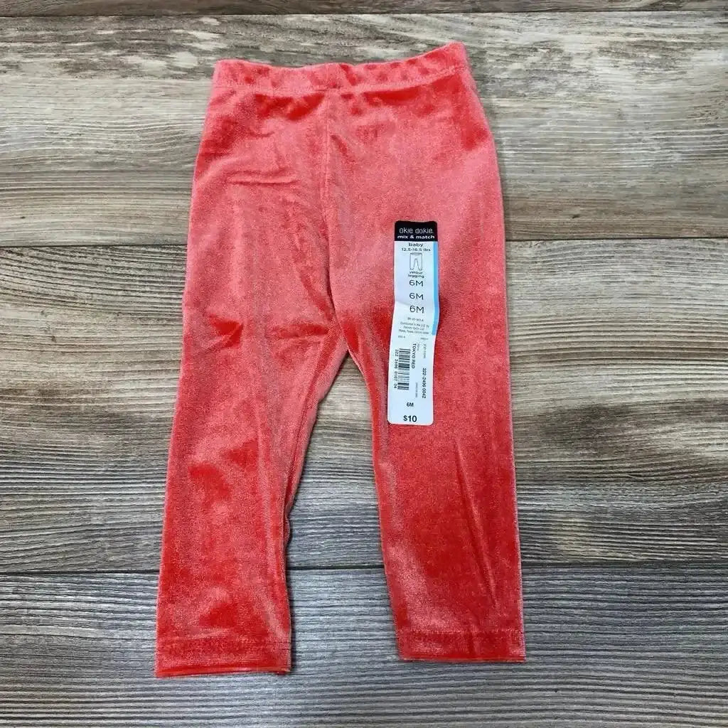 Front view of NEW Okie Dokie velour leggings in size 6M showcasing red velour fabric with a wood-grain background